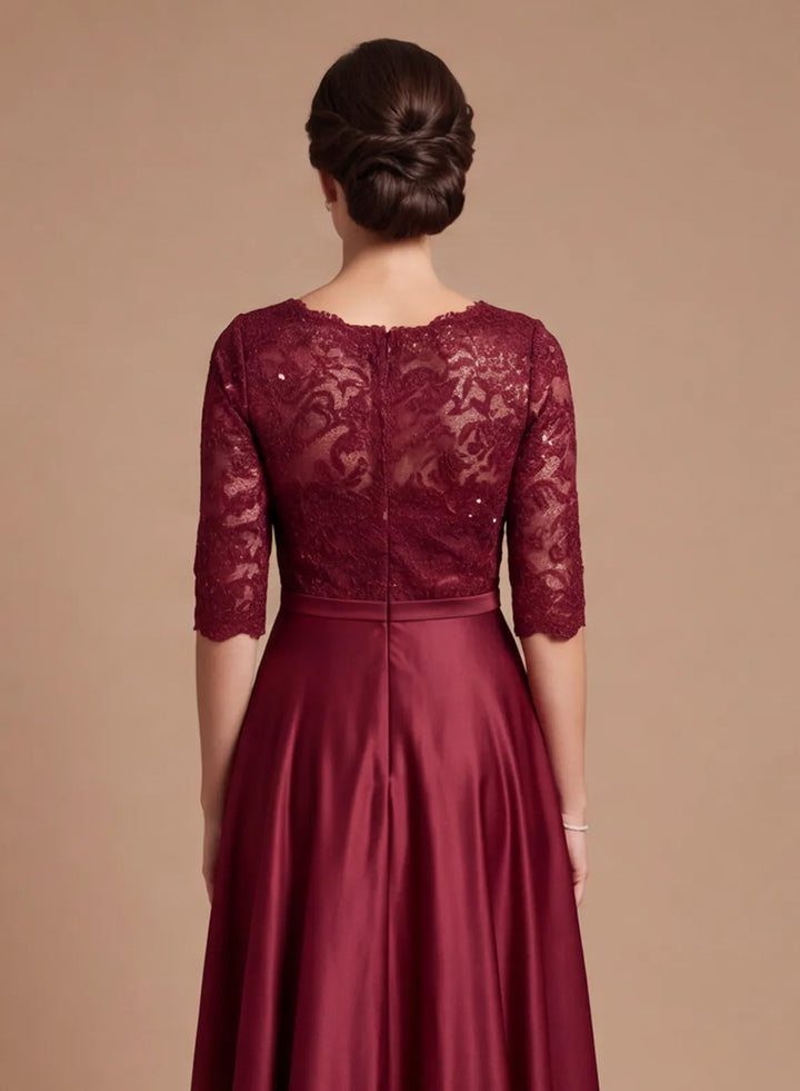 Back detail of burgundy lace bodice with intricate floral lace pattern and flowing satin skirt