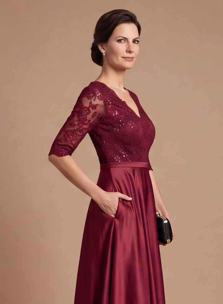 Side detail of burgundy lace bodice and flowing satin skirt on an elegant formal evening gown