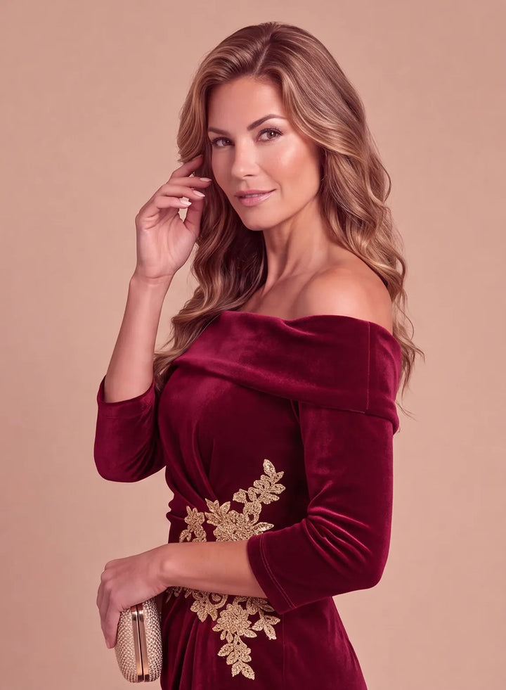 Side view of a burgundy velvet off-the-shoulder dress with three-quarter sleeves and gold floral waist embellishment.