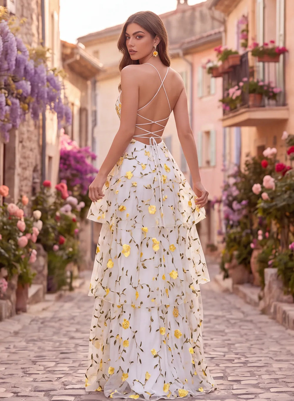 Back view of a butter yellow floral prom gown featuring thin straps, a lace-up corset back, and a flowing tiered skirt.