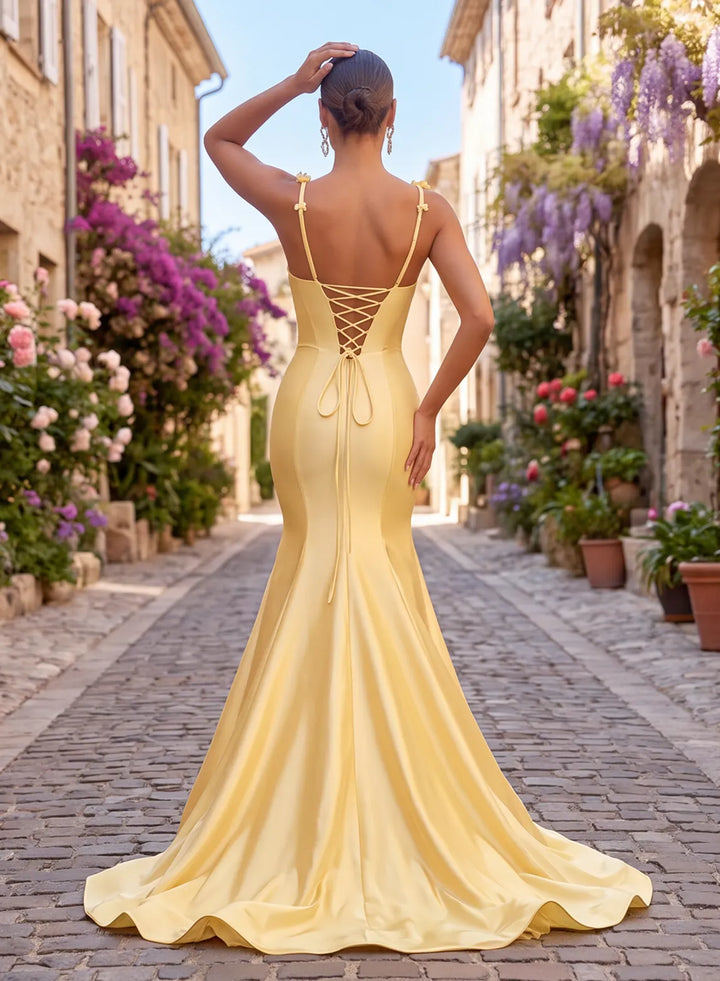 Back view of a butter yellow satin mermaid prom dress with lace-up corset back and floral shoulder straps.