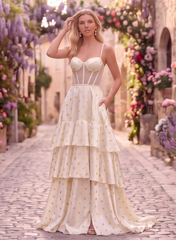 Ivory prom dress with gold polka dots, corset bodice, spaghetti straps and tiered skirt, front view.