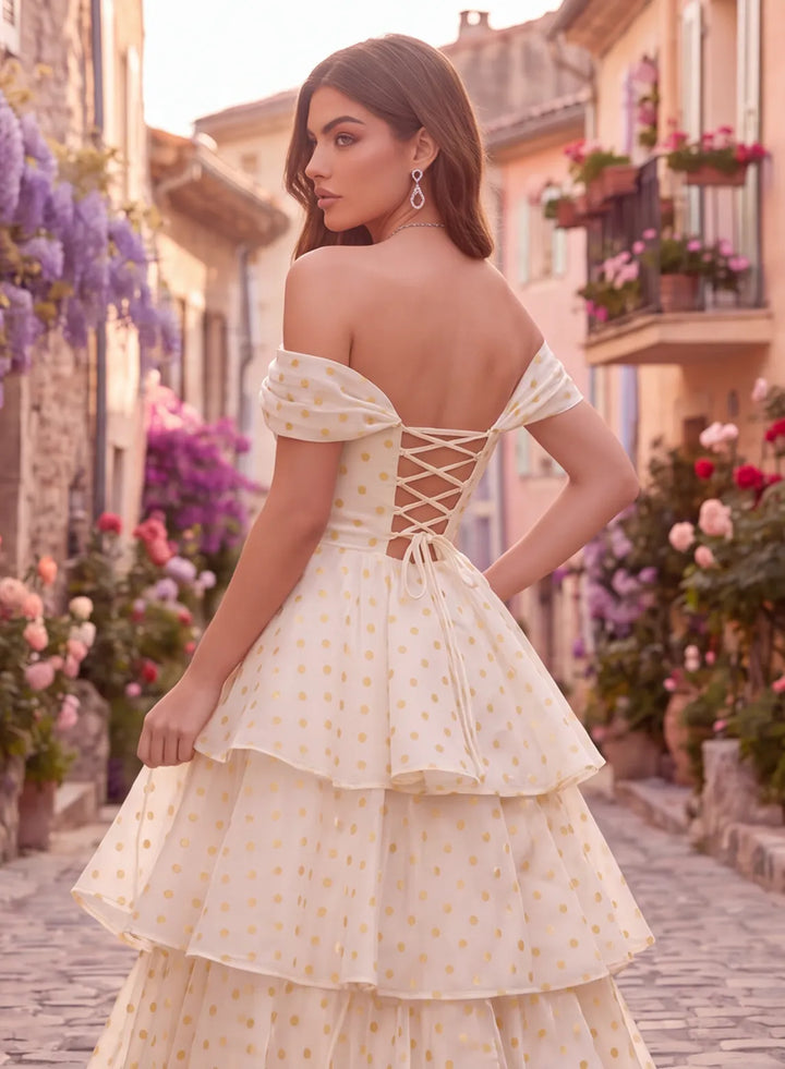 Back view of an ivory and gold polka dot off shoulder prom dress with a lace-up corset back and layered floor length skirt.

复制 ALT