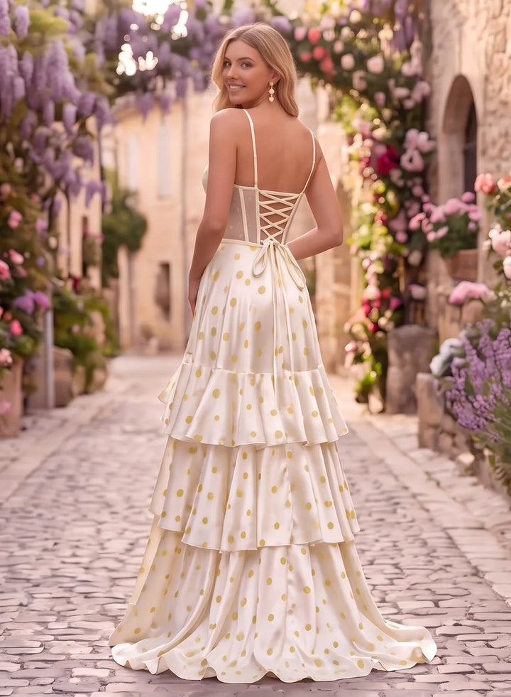 Back view of an ivory polka dot prom gown featuring a lace-up corset back, thin straps and a flowing tiered skirt.