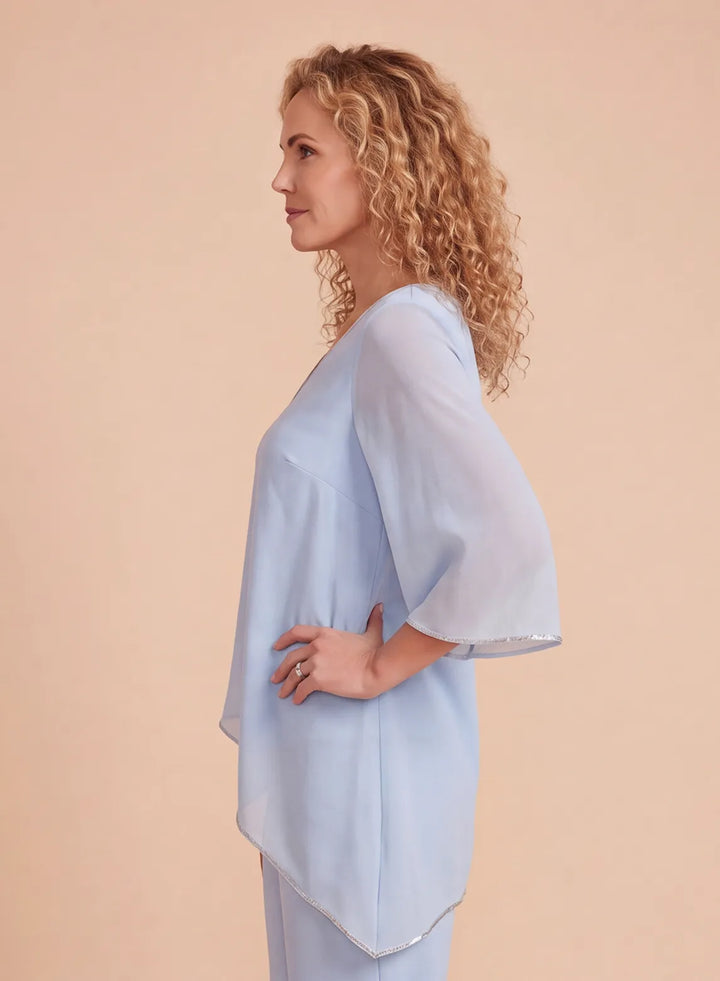 Side detail of a light blue chiffon pantsuit showing the flowing asymmetric hem and metallic trim