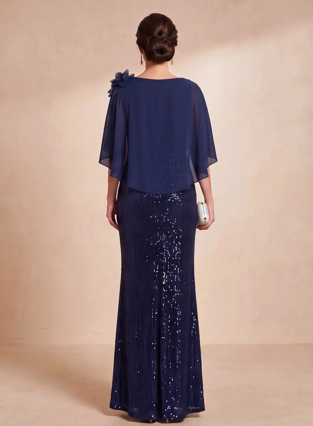 Back view of navy blue sequin formal gown with flowing chiffon cape