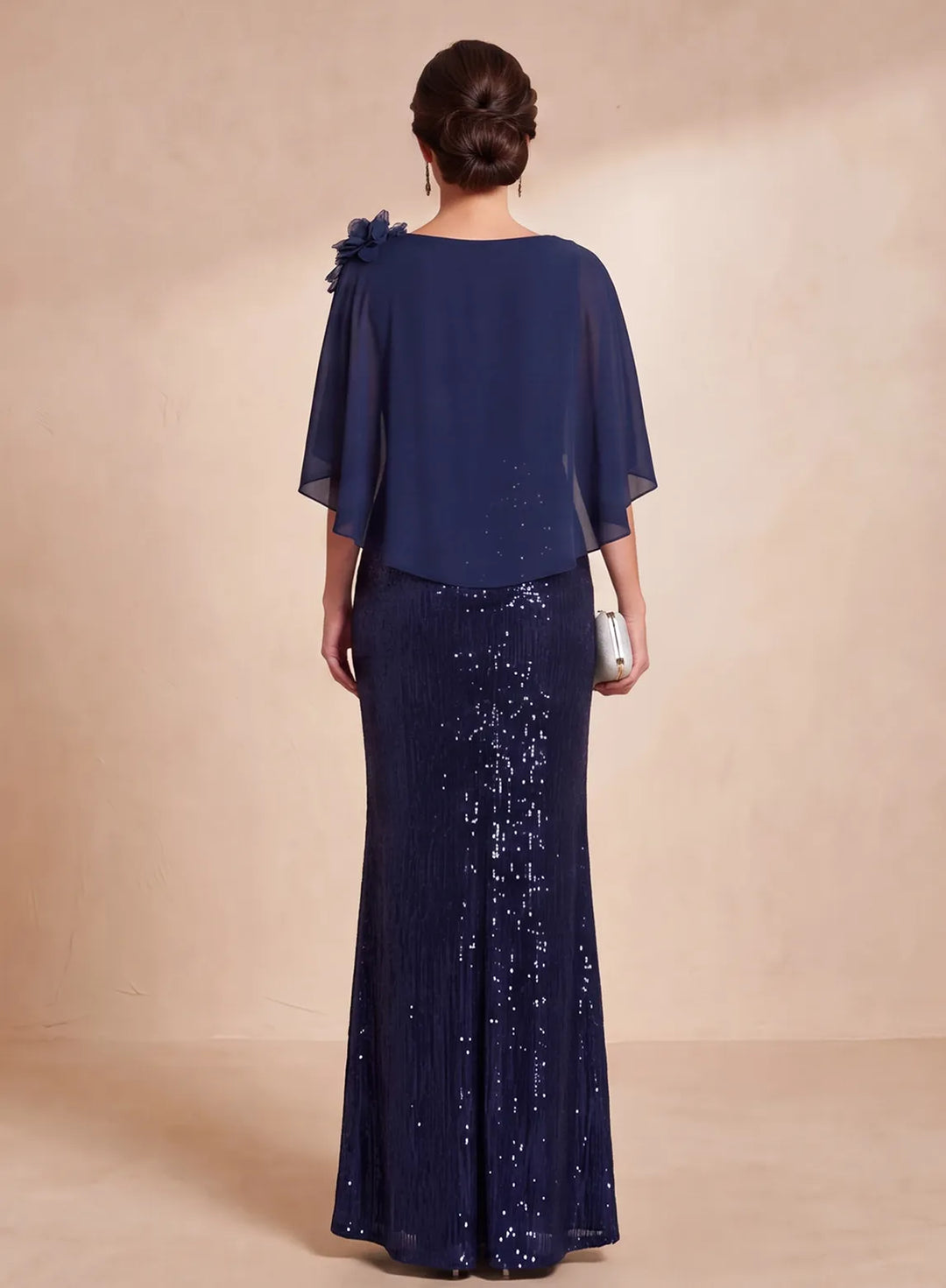 Back view of navy blue sequin formal gown with flowing chiffon cape